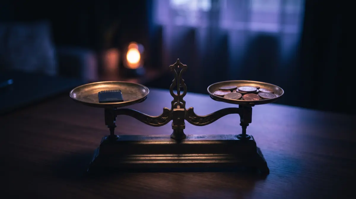 A brass balance scale weighing a single memory card against a small stack of coins