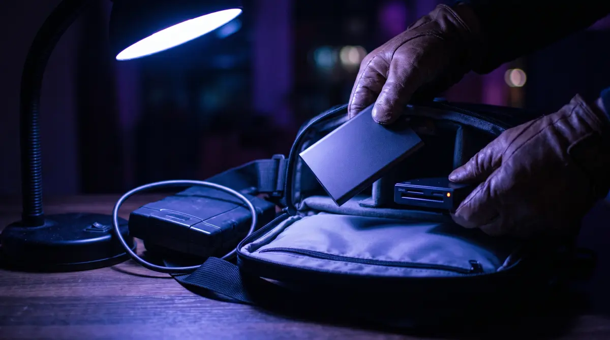 Hands pack a slim drive and card reader into a bag, leaving an old drive