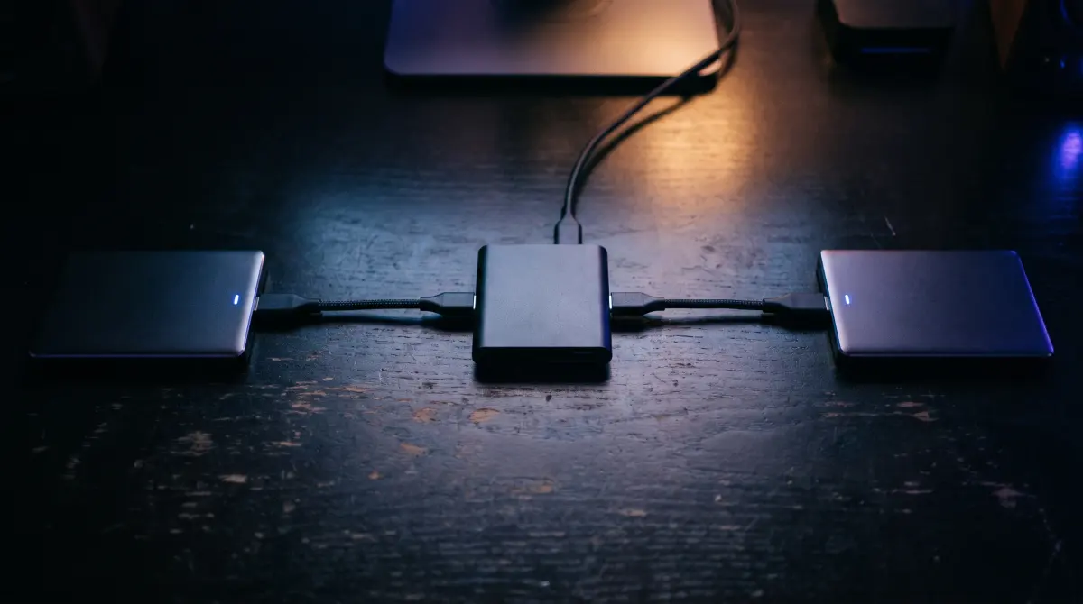A card reader in the center with cables running to two glowing portable drives